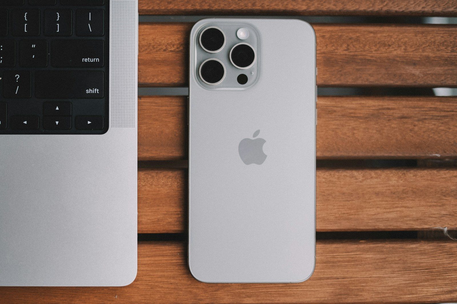 An iPhone and a laptop on a wooden table